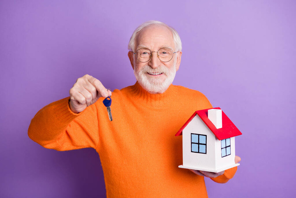Photo of satisfied aged man hand hold key little house have good mood isolated on violet color background - 写真・画像