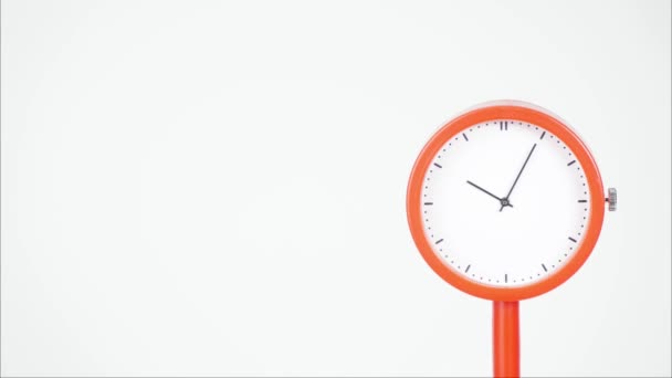 Beyaz kadranlı yuvarlak saat. Bir kol var ve saatin kenarı turuncu. Siyah saat gösterilecek numara yok ama saat 10: 00-10: 40 arasında saat yönünde dönmeye uygun bir saat işareti var.. - Video, Çekim