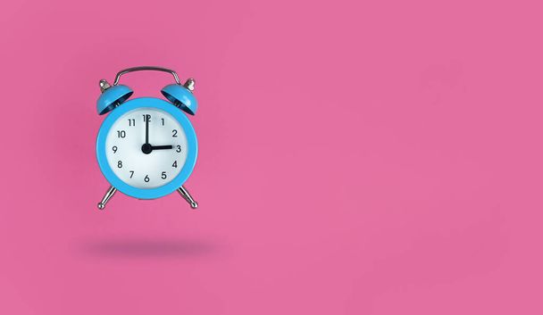 Levitating blue alarm clock on a pink background with copy space. - Фото, зображення