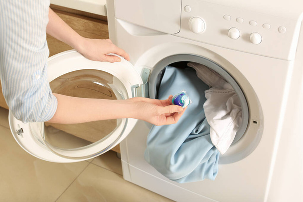 Woman putting laundry detergent capsule into washing machine indoors, closeup - Φωτογραφία, εικόνα