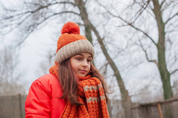 Meisje van 10 jaar. Tiener in oranje jasje. Tiener meisje in oranje jas, oranje hoed en sjaal - Foto, afbeelding