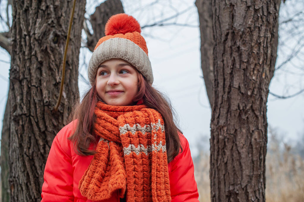 Dziesięciolatka. Nastolatek w pomarańczowej kurtce. Nastolatka w pomarańczowej kurtce, pomarańczowym kapeluszu i szaliku - Zdjęcie, obraz