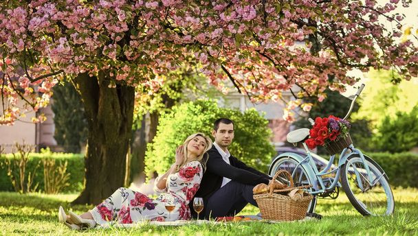 Happy loving couple relaxing in park with food. Romantic picnic with wine. Give uncommon, unique gifts spontaneously. Enjoying their perfect date. Couple in love picnic date. Spring weekend - Foto, Bild