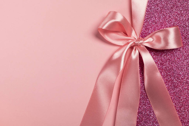 Vaaleanpunainen lahja kiiltävä kortti, todistus tai tekstuuri lahjapakkauksessa nauha keula. Ystävänpäivä, äitienpäivä, syntymäpäivä, vuosipäivä, joulutausta. Top view, tasainen lay, kopioi tilaa, malli suunnittelu - Valokuva, kuva