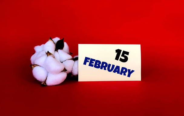 15 de febrero en una pegatina amarilla.Junto a ella está el algodón sobre un fondo rojo.Último mes de invierno.Calendario para febrero. - Foto, Imagen