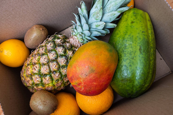 Pineapple, mango, kiwi and oranges in a box. Vegan concept. Fresh fruits. - Fotó, kép