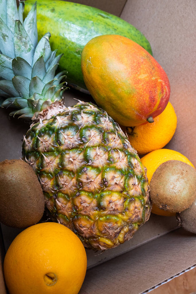 Pineapple, mango, kiwi and oranges in a box. Vegan concept. Fresh fruits. - Φωτογραφία, εικόνα