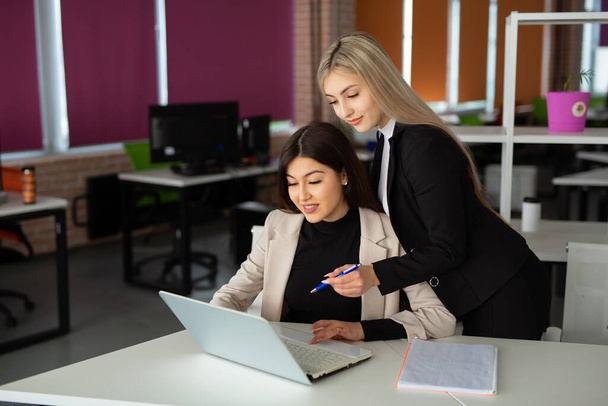 two beautiful young women in the office with a laptop  - Foto, Imagen