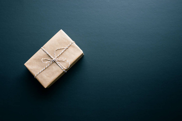 Caja de regalo marrón en estilo bricolaje en pizarra oscura background.giving y cocepts aniversario idea.top ver - Foto, imagen