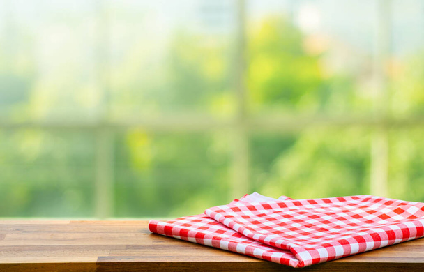 Blauw gecontroleerd tafelkleed op hout met wazige groene bokeh uit de raamkeuken achtergrond.Zomer en picknick concepten.Ontwerp voor belangrijke visuele voedsel en drank producten. - Foto, afbeelding