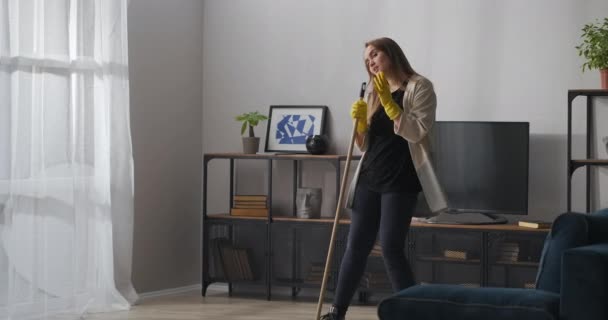teenager dívka zpívá v mop jako v mikrofonu, mytí podlahy a tanec v bytě, dobrá a radostná nálada, pomoc kolem domu - Záběry, video