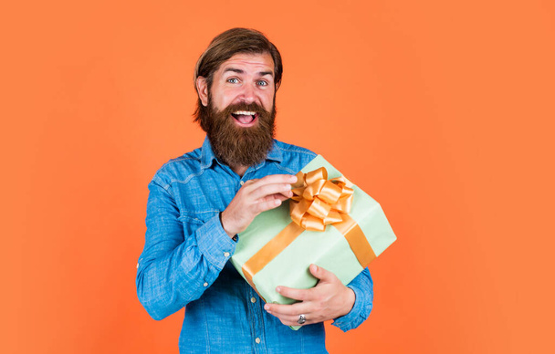 volwassen man met baard en trendy kapsel hold geschenkdoos, korting - Foto, afbeelding