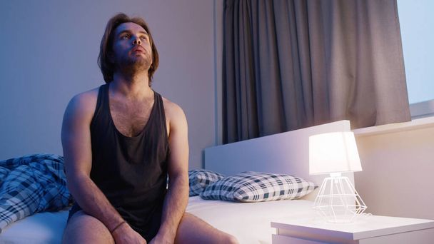 Young caucasian man sitting on the bed . Insomnia problem, mental disorder or depression - Fotó, kép