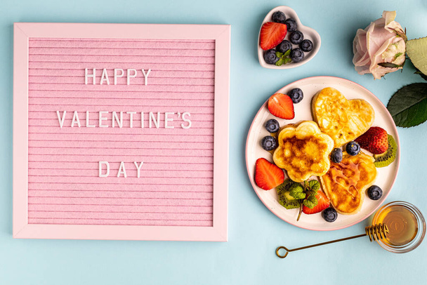 Valentijnsdag plat lag met hartvormige pannenkoeken op een blauwe achtergrond. Valentijnsdag concept. Bovenaanzicht - Foto, afbeelding