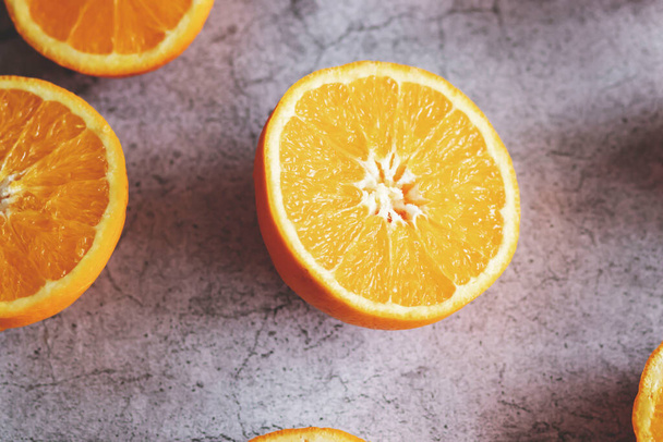 Las mitades naranjas están sobre la mesa. Sobre un fondo gris y blanco. - Foto, Imagen