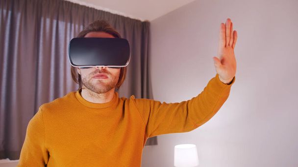 Νεαρός με VR ακουστικά που βιώνουν εικονική πραγματικότητα - Φωτογραφία, εικόνα