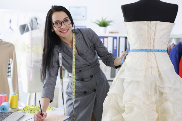 Mujer costurera escribir tamaños de vestido de novia - Foto, Imagen