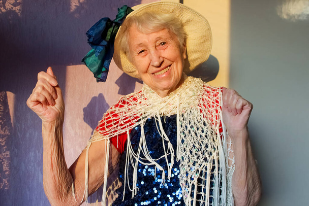 Glücklich lächelnde lustige Seniorin, die zu Hause Perlen trägt - Foto, Bild