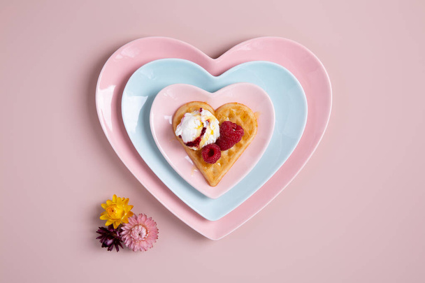 Gofry w kształcie serca z lodami i jagodami na różowym tle. Smaczne śniadanie. Szczęśliwych Walentynek. Widok z góry. - Zdjęcie, obraz