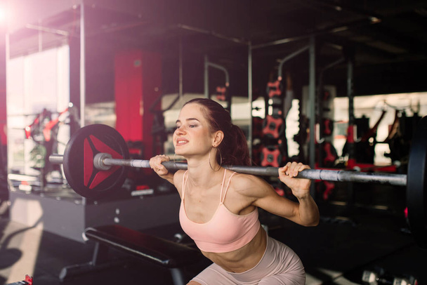 Chica atlética en ropa deportiva realiza ejercicios con una barra, mancuernas. Fitness, entrenamiento, estilo de vida saludable - Foto, Imagen