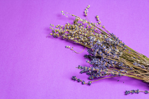 Ramo de flores secas de lavanda sobre un fondo lila. Flores fragantes, ingrediente indispensable, juego de texto, disposición plana - Foto, Imagen