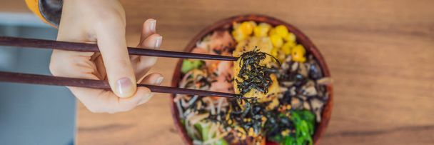 Woman eating Raw Organic Poke Bowl with Rice and Veggies close-up on the table. Top view from above horizontal BANNER, LONG FORMAT - Fotografie, Obrázek