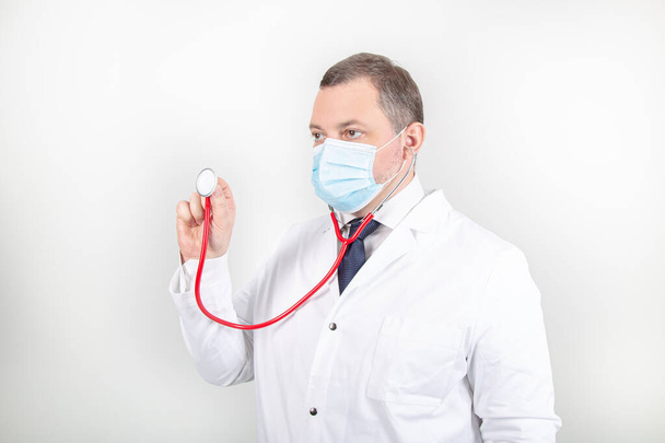 Médico en bata blanca y máscara con estetoscopio con diferentes gestos  - Foto, imagen