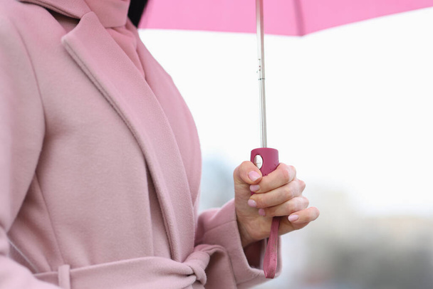 Жіноча рука тримає рожеву парасольку під дощем крупним планом
 - Фото, зображення
