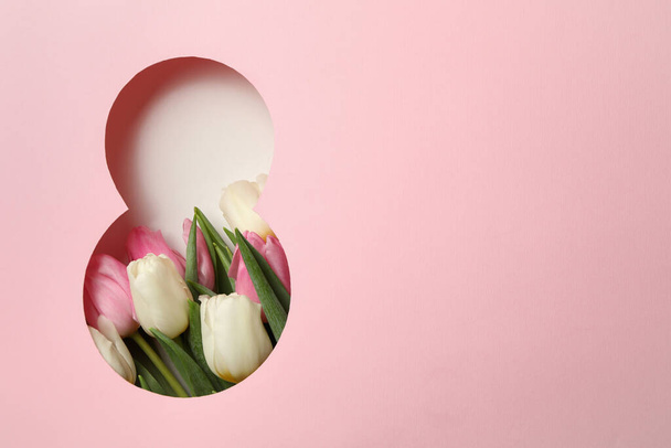 Papierschnitt Acht aus rosa Hintergrund und Tulpen auf weißem Hintergrund - Foto, Bild