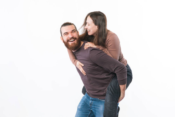 Foto de feliz jovem casal se divertindo e abraçando sobre fundo branco - Foto, Imagem