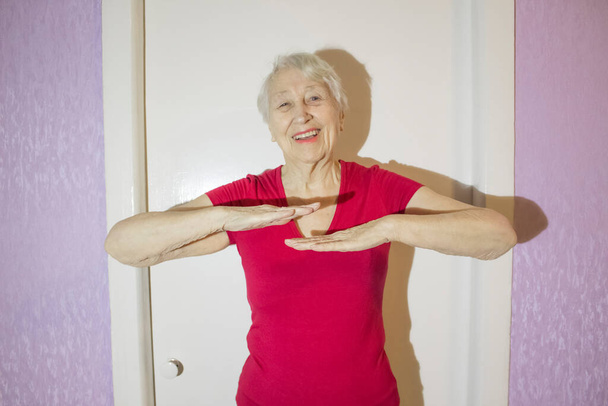 Старша жінка в спортивному одязі під час гімнастичних вправ у вітальні вдома
. - Фото, зображення
