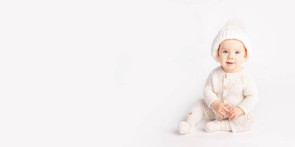 baby crawls in a warm suit and hat on a white isolated background, space for text, banner - Foto, imagen