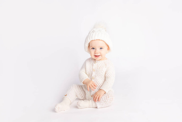 baby in een warm pak en hoed op een witte geïsoleerde achtergrond, ruimte voor tekst - Foto, afbeelding