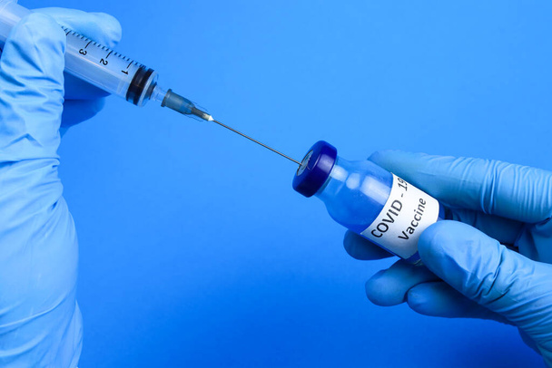 vacuna contra el coronavirus y una jeringa en las manos de un médico o enfermero. El concepto de la lucha contra el covidio - Foto, Imagen