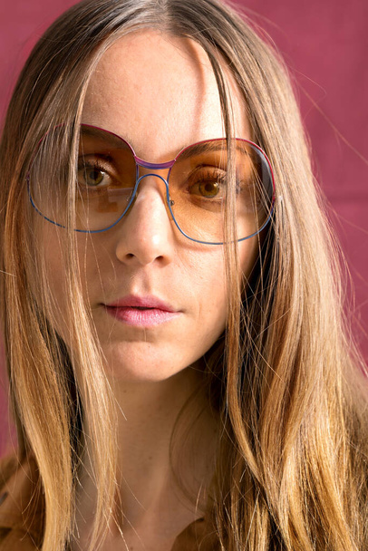 Close-up of a young woman without makeup with intended look. Wear smoky glasses.  - 写真・画像