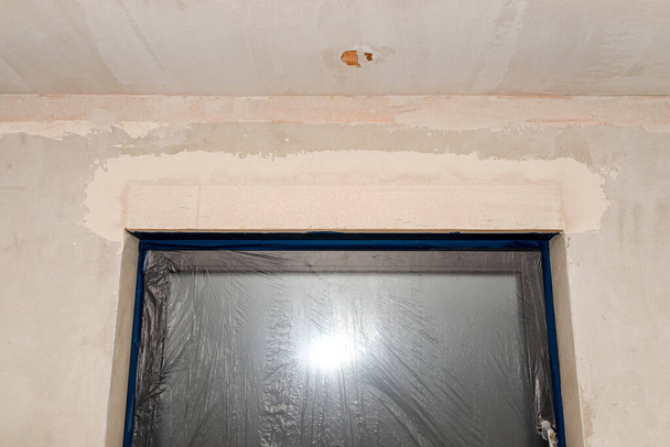 Εγκατάσταση για εξωτερικά ρολά από γυψοσανίδες στο εσωτερικό του κτιρίου, τα παράθυρα καλύπτονται με προστατευτικό φύλλο. - Φωτογραφία, εικόνα