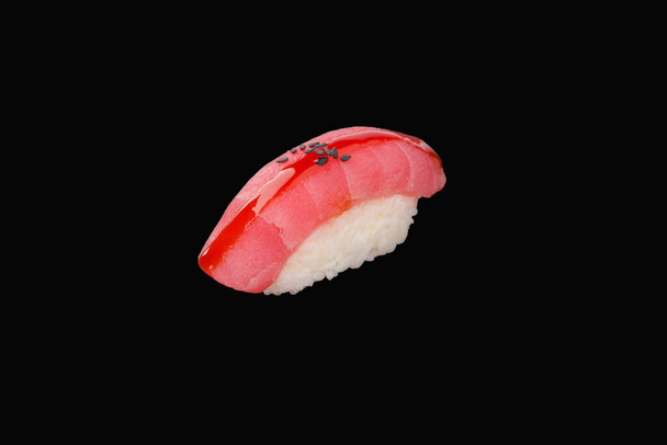 Nigiri sushi con atún, semillas de sésamo, salsa unagi aislada sobre fondo negro - Foto, Imagen