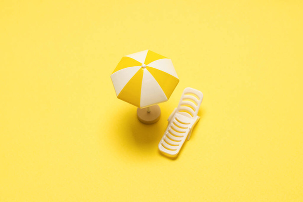 Sun lounger and yellow umbrella on a yellow background. - Zdjęcie, obraz