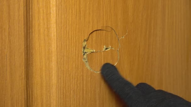Mannen handen in zwarte handschoenen meten een gat in de deur met een meetlint, - Video