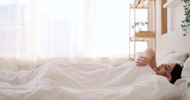 美しい女性が目を覚ますとベッドでストレッチ - 映像、動画