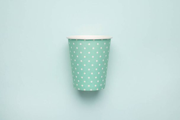 Paper cup with polka dot print green color on mint background. Eco friendly takeout cup for drink top view - 写真・画像