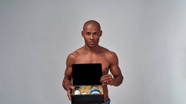 Muscular male holding a box with several creams - Foto, afbeelding