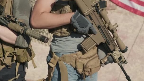 Kantelen-up portret van jonge Amerikaanse leger infanterie officieren in camouflage kleding en zonnebril met sluipschutters geweren op het platteland met Amerikaanse vlag op de achtergrond op zoek naar camera - Video