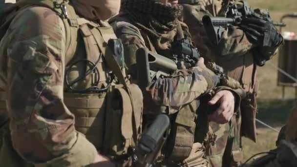 Handheld beelden van brigade van inlichtingenagenten in camouflage uniform met sluipschuttergeweren die vooruit kijken op het platteland - Video
