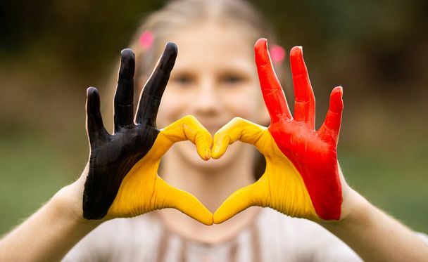 Kid hands painted in Belgium flag color show symbol of heart and love gesture  - Photo, Image