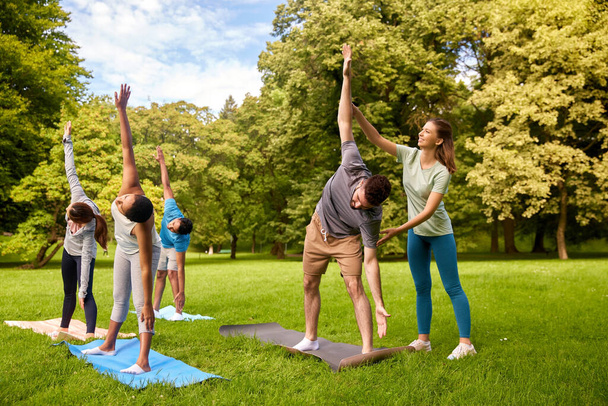 group of people doing yoga with instructor at park - Valokuva, kuva