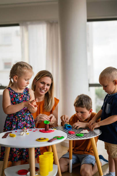 Mother teaches preschooler kids to do craft items. Family, children, education, happiness concept. - Фото, зображення
