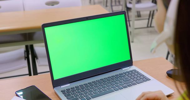 asian woman has online learning with green screen laptop computer in the classroom at school - Фото, изображение