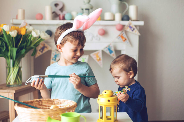 Velikonoce. Chlapec a dívka malují velikonoční vajíčka. Velikonoční výzdoba. - Fotografie, Obrázek