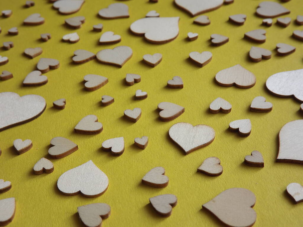 corazones de madera de diferentes tamaños sobre un fondo amarillo. día de San Valentín, una declaración de amor - Foto, Imagen